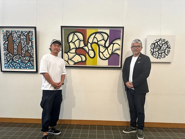 写真左から アヒ氏・山西氏 アヒ氏が寄贈されたアート作品の前で